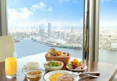 画像：大きな窓の外には青空が広がり、その手前には色とりどりの料理が並んでいる