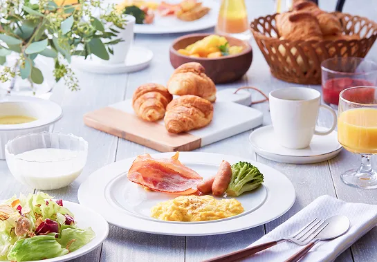 写真：洋風朝食のテーブルセッティング。クロワッサンと卵料理、ジュースやコーヒー付き